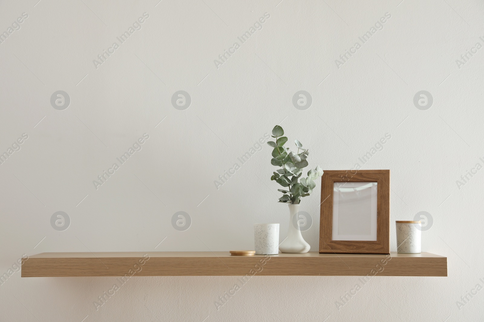 Photo of Wooden shelf with photo frame and decorative elements on light wall