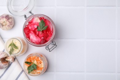 Photo of Delicious sauerkraut prepared according to different recipes on white tiled table, flat lay. Space for text