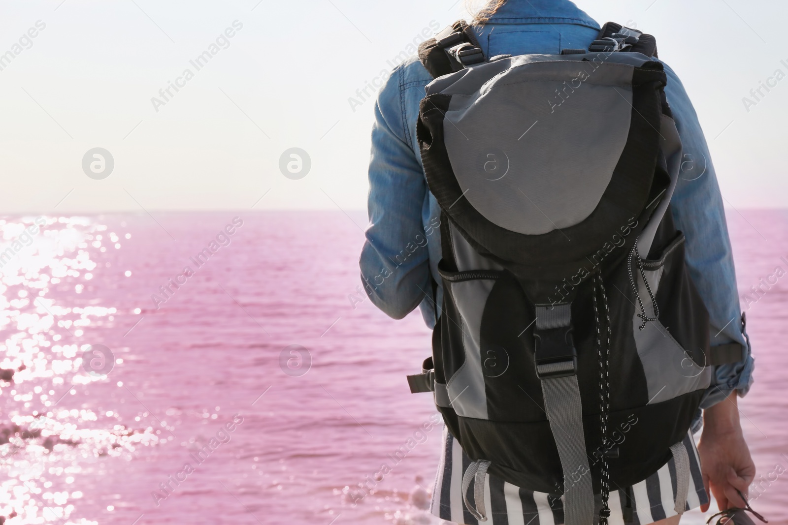 Photo of Woman with backpack on coast of pink lake
