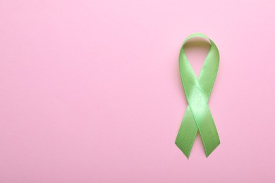 Photo of World Mental Health Day. Green ribbon on pink background, top view with space for text