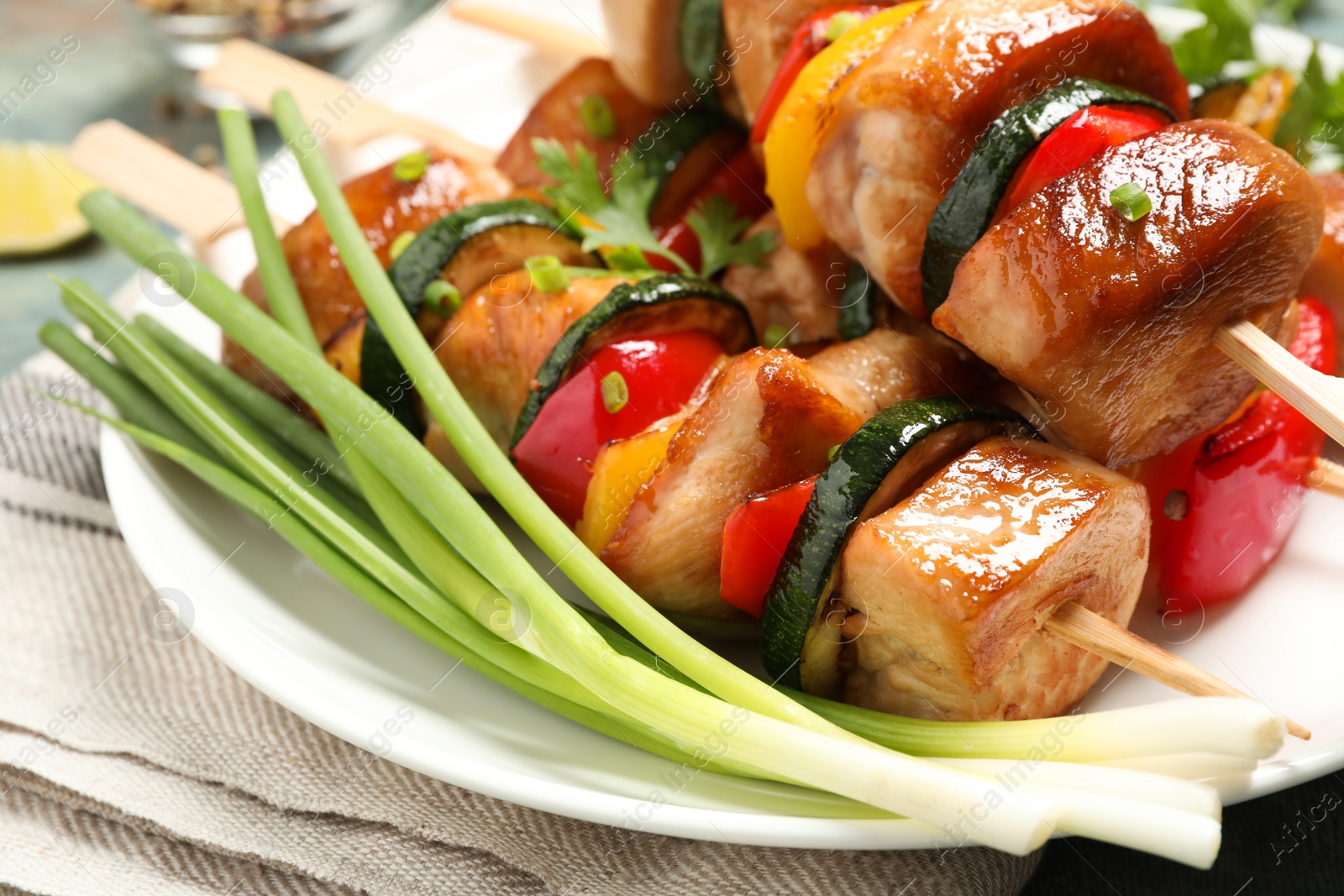 Photo of Delicious chicken shish kebabs with vegetables and parsley on plate, closeup