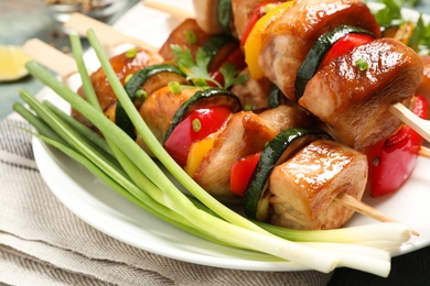 Delicious chicken shish kebabs with vegetables and parsley on plate, closeup