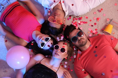 Group of friends lying on messy floor after party, top view