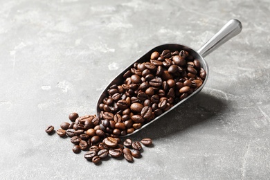 Photo of Scoop with roasted coffee beans on grey background