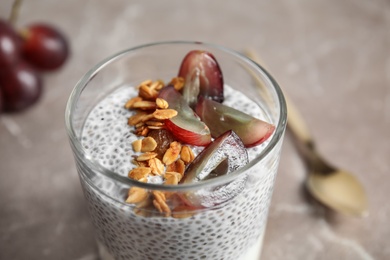 Photo of Tasty chia seed pudding with granola and grape on table, closeup