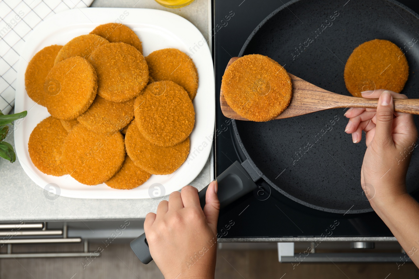 Photo of Woman cooking breaded cutlets in frying pan on stove, top view