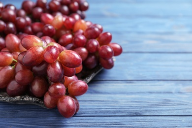 Photo of Fresh ripe juicy grapes on blue wooden table. Space for text