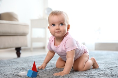Cute baby girl playing on floor in room