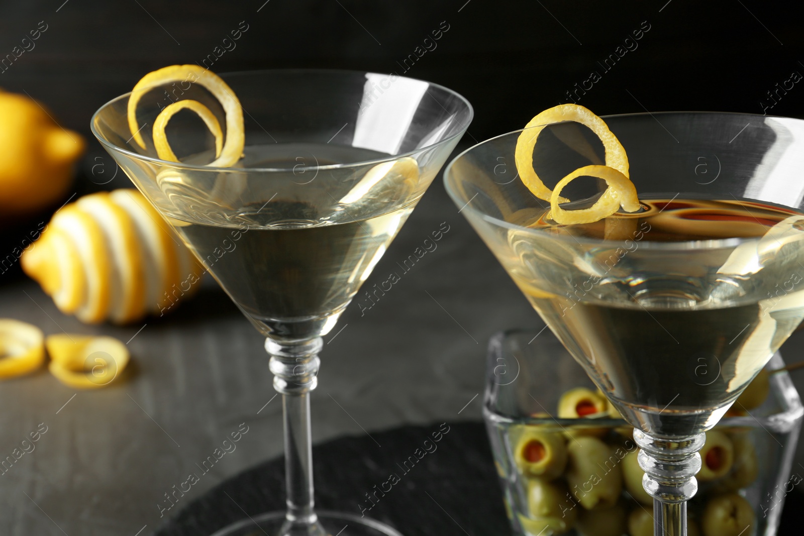 Photo of Glasses of Lemon Drop Martini cocktail with zest on grey table, closeup