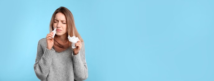Photo of Sick young woman using nasal spray on light blue background