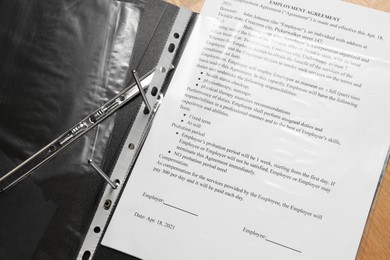 Photo of File folder with punched pocket and document on wooden table, closeup