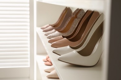 Different stylish women's shoes on shelving unit in dressing room