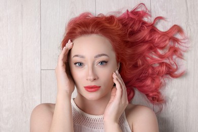 Trendy hairstyle. Young woman with colorful dyed hair on white wooden background, top view