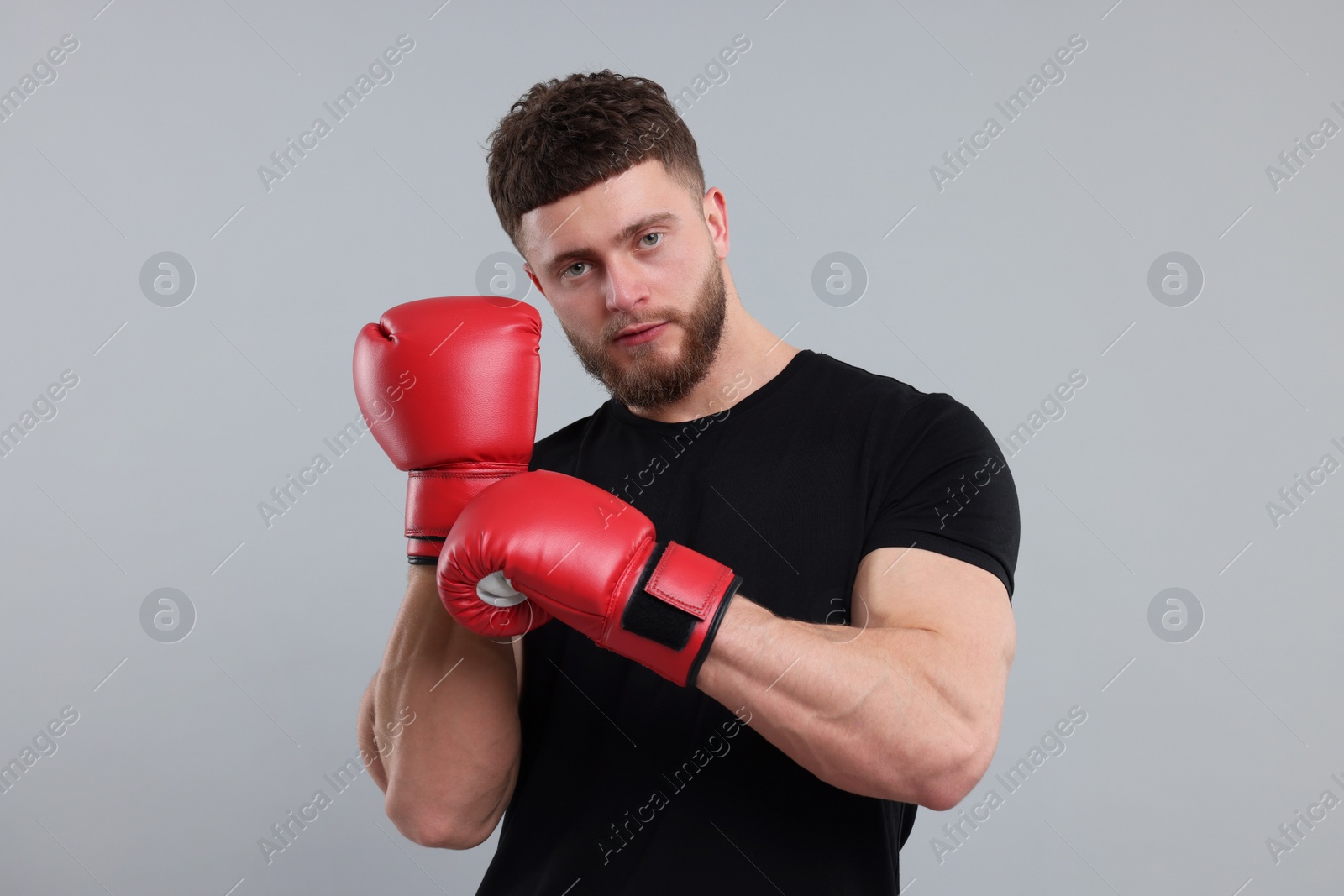 Photo of Man putting on boxing gloves against grey background