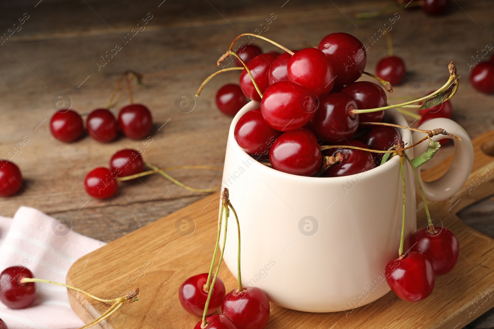 Photo of Cup of delicious cherries on cutting board, closeup view. Space for text