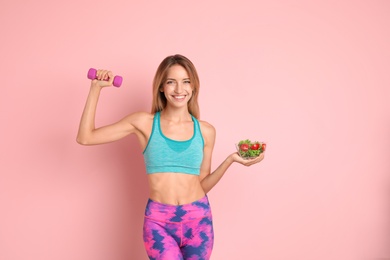Photo of Happy slim woman in sportswear with salad and dumbbell on color background. Weight loss diet