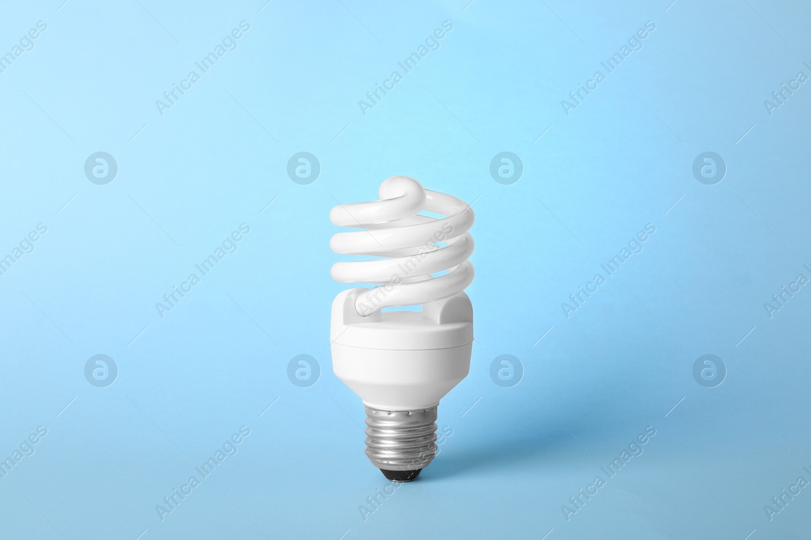 Photo of Modern fluorescent lamp bulb on light blue background