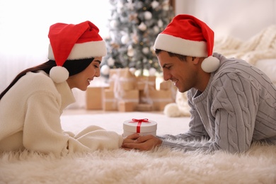 Photo of Couple holding Christmas gift box in living room