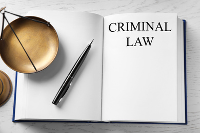 Image of Scales of justice and book on white wooden table, top view. Criminal law concept 