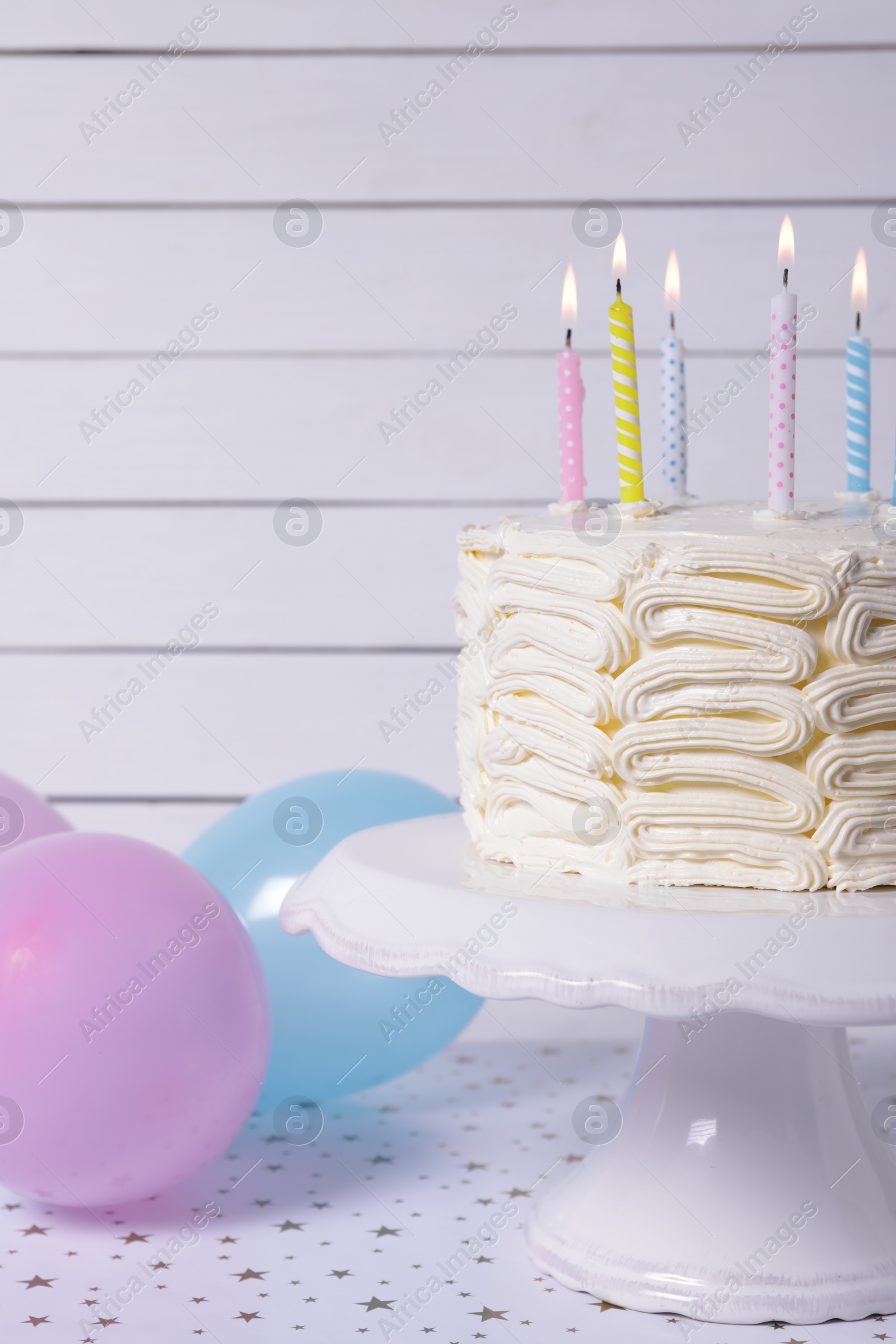 Photo of Delicious cake with burning candles and festive decor on white table, closeup