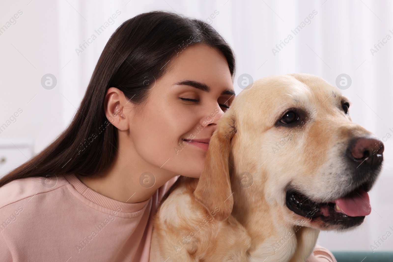 Photo of Happy woman with cute Labrador Retriever at home, closeup