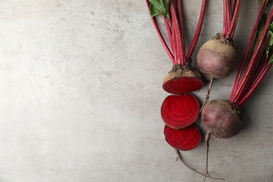 Cut and whole raw beets on light grey table, flat lay. Space for text