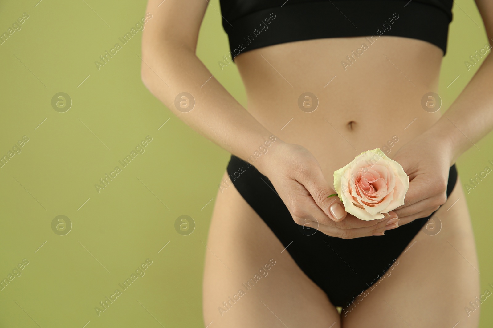 Photo of Gynecology. Woman in underwear with rose flower on green background, closeup. Space for text