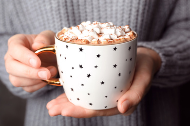 Photo of Woman holding cup of delicious hot cocoa with marshmallows , closeup