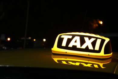 Taxi car with yellow sign outdoors at night, closeup