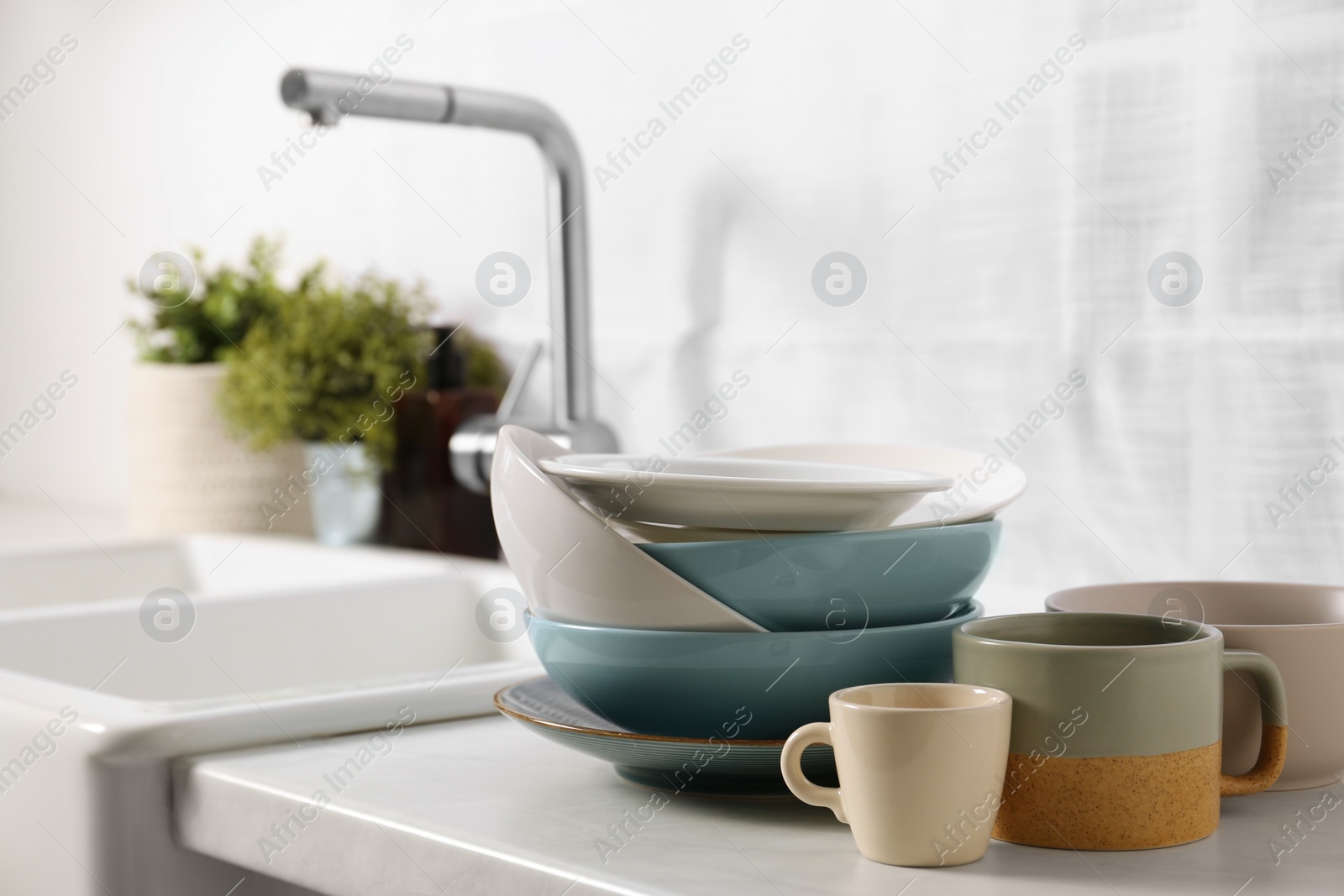 Photo of Clean tableware on light countertop near sink in kitchen