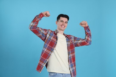 Portrait of excited young man on light blue background