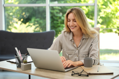 Photo of Pretty young woman working with laptop in office