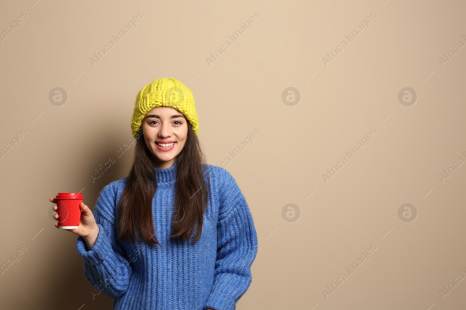 Photo of Young woman in sweater with cup of hot coffee on color background, space for text. Winter season