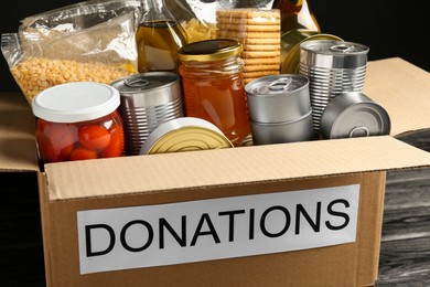 Photo of Donation box with food on black table, closeup