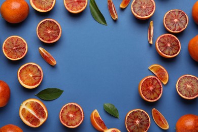 Photo of Frame of ripe sicilian oranges and leaves on blue background, flat lay. Space for text