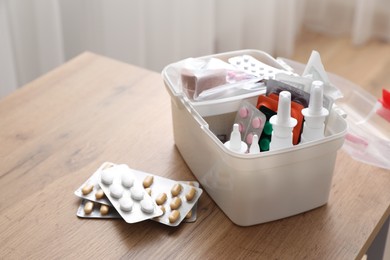 Photo of First aid kit and medicaments on wooden table indoors, closeup. Space for text