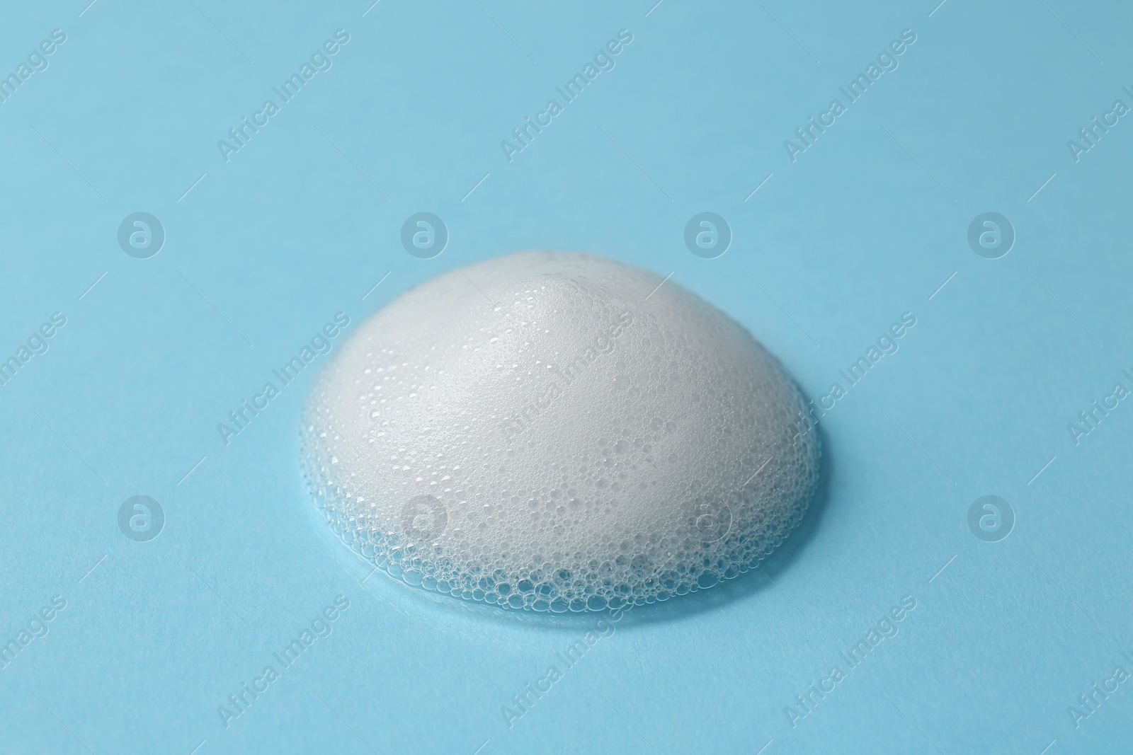 Photo of Foam on light blue background. Face cleanser, skin care cosmetic