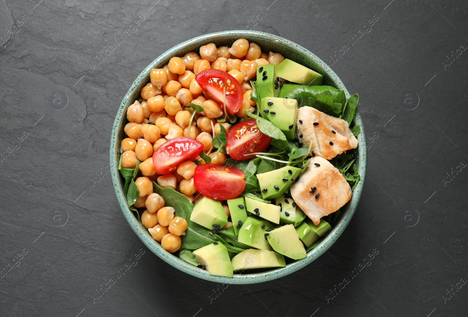 Photo of Delicious avocado salad with chickpea on black table, top view
