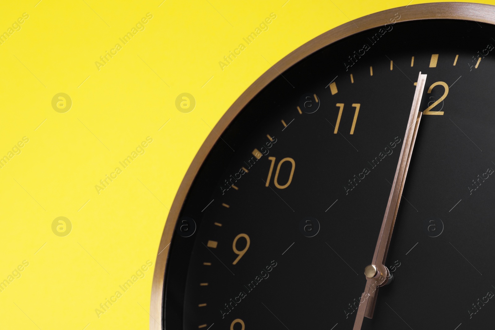 Photo of Closeup view of stylish round clock on yellow background, space for text. Interior element