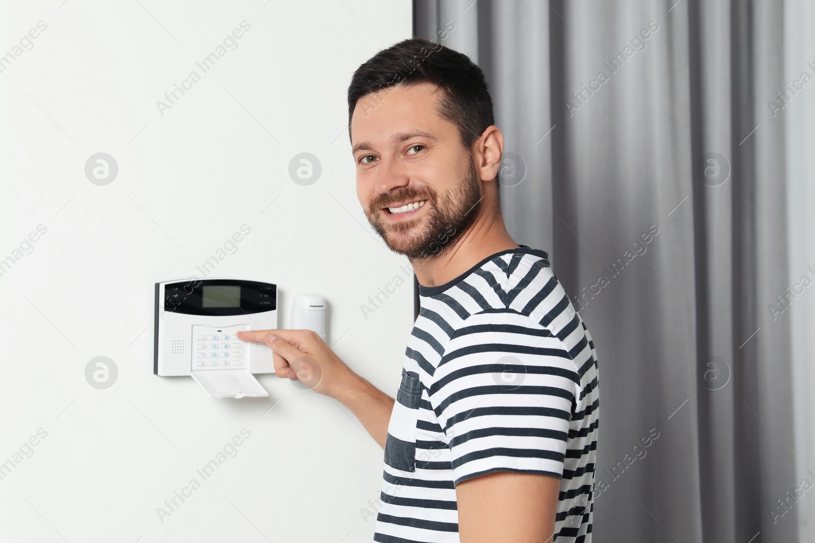 Photo of Man entering code on home security system indoors