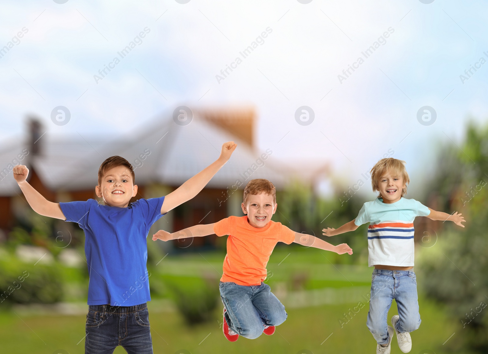 Image of Happy boys jumping near house. School holidays