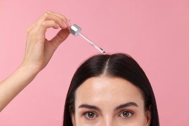 Photo of Woman applying hair serum on pink background, closeup. Cosmetic product