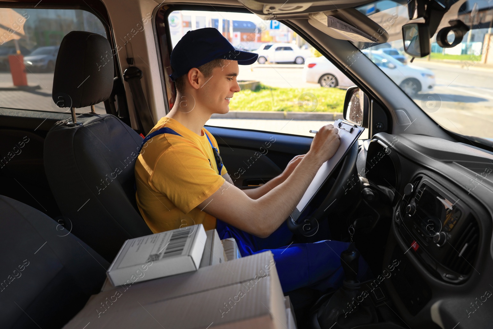 Photo of Courier with clipboard checking packages in car