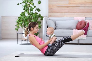 Photo of Young sportive woman doing exercise with her son at home. Fitness training