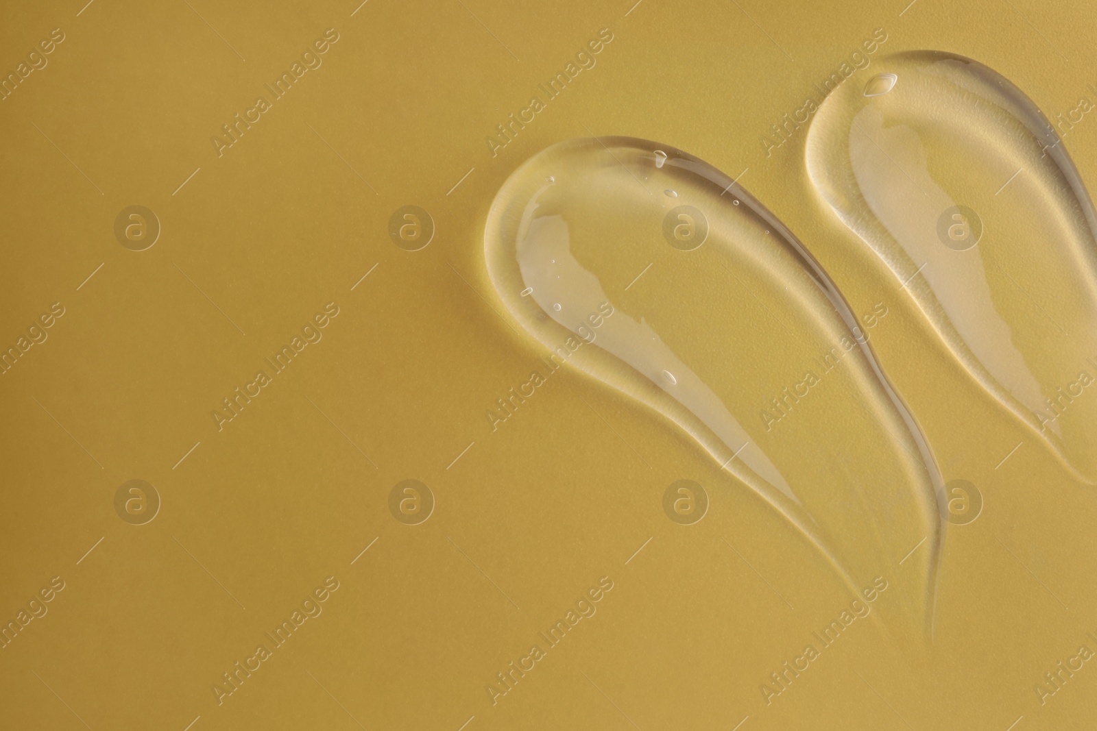 Photo of Sample of transparent gel on dark yellow background, top view. Space for text