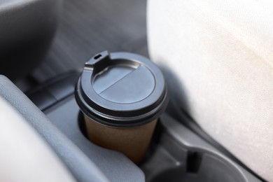 Photo of Coffee to go. Paper cup with tasty drink in holder inside of car, closeup