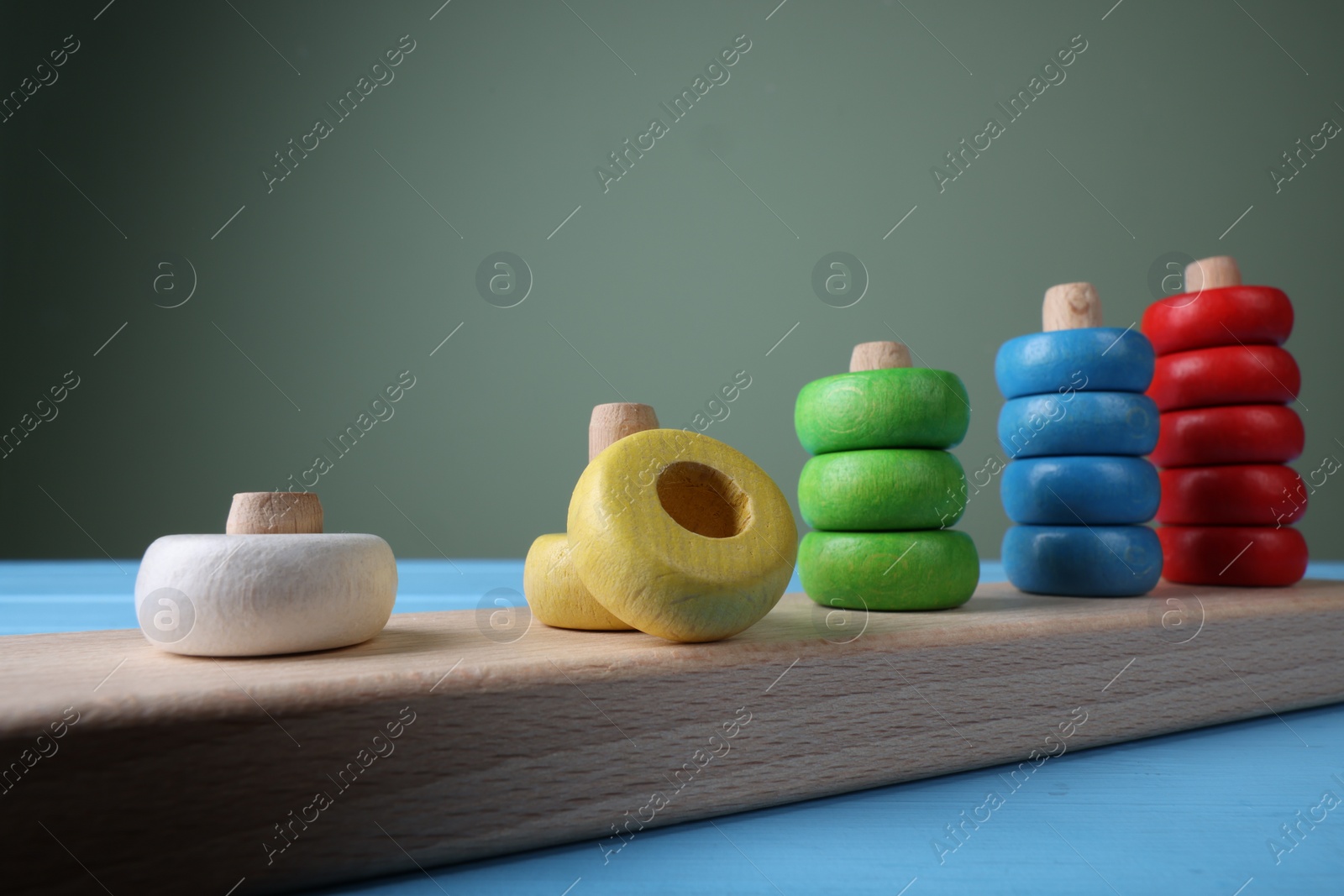 Photo of Stacking and counting game pieces on light blue table against grey wall, closeup. Motor skills development