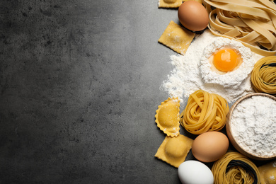 Flat lay composition with different types of pasta on grey table. Space for text