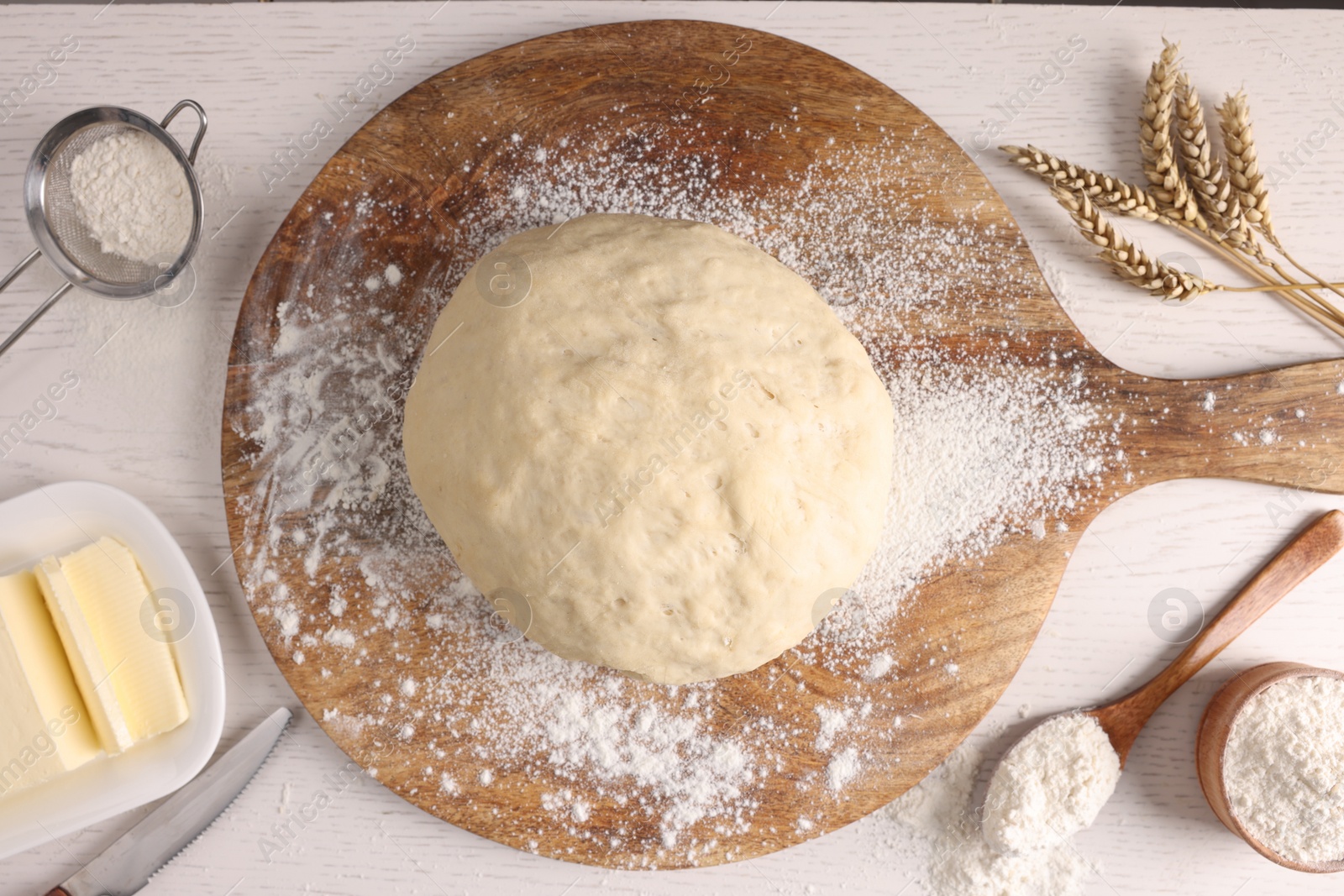 Photo of Fresh dough sprinkled with flour and other ingredients on white wooden table, flat lay