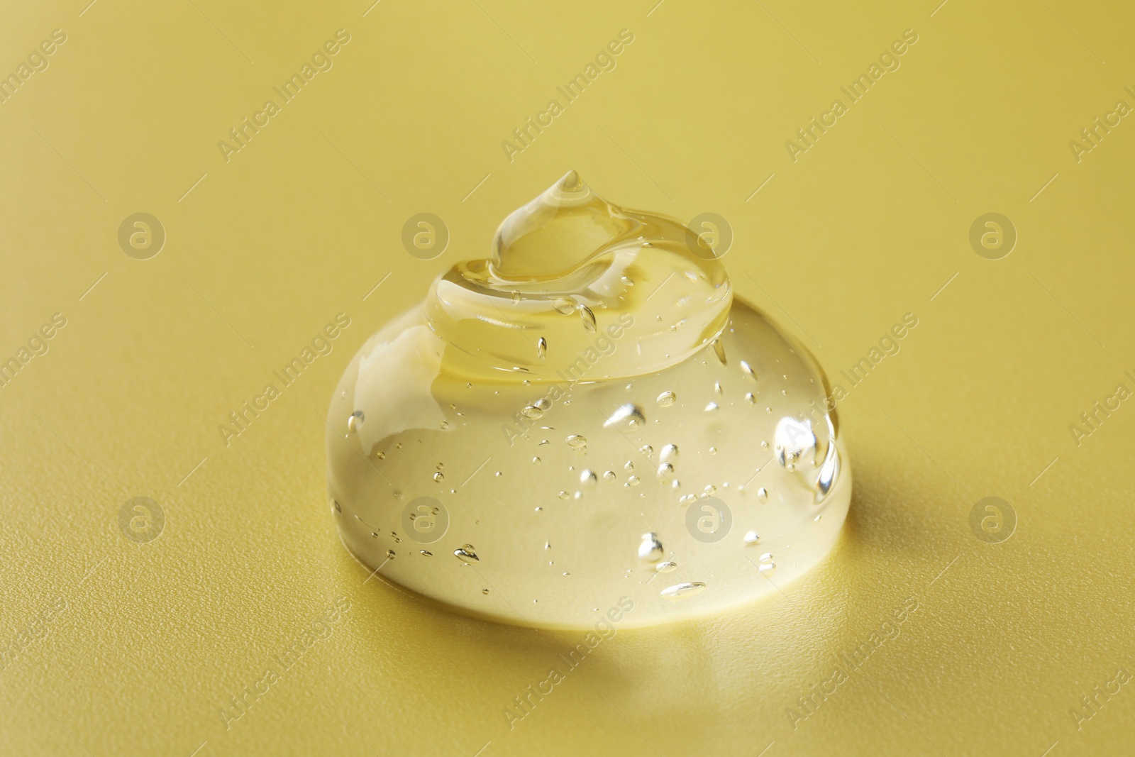 Photo of Sample of clear cosmetic gel on yellow background, closeup